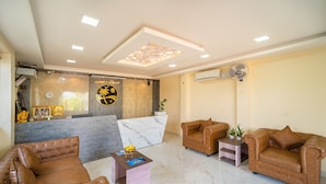 A reception area with a marble reception desk, two leather sofas, a small side table, and a wall-mounted fan.
