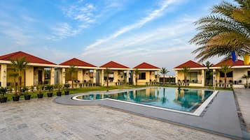 Un resort con piscina, varias villas con techos rojos y palmeras.