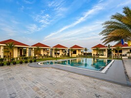 Un resort con piscina, varias villas con techos rojos y palmeras.