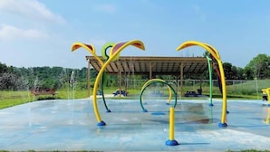 Un espace de jeux aquatiques extérieur doté de plusieurs jets d’eau et d’arcs.