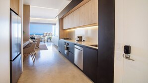 A modern kitchen with a view of the sea, a dining area with chairs, and a large window. - Romantic Zone’s Largest Rooftop | Luxe Ocean Views (Puerto Vallarta)