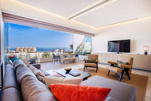 Ein modernes Wohnzimmer mit großem Fenster, einer Couch, einem Couchtisch und einem Fernseher.