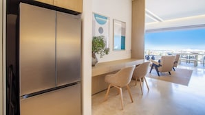 A modern kitchen with stainless steel appliances, a wooden countertop, and a seating area with chairs and a table. - Romantic Zone’s Largest Rooftop | Luxe Ocean Views (Puerto Vallarta)