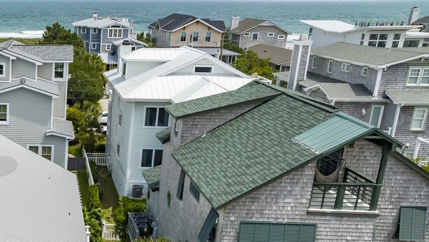 Un quartier résidentiel situé sur la côte, composé de plusieurs maisons, dont une demeure remarquable avec un toit végétalisé et un balcon.