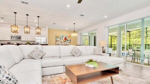 A modern living room with a sectional sofa, a coffee table, and a large window offering a view of the outdoors.