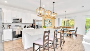 A modern kitchen with white cabinets, stainless steel appliances, and a large island with bar stools.