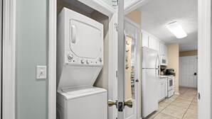 A laundry room with a front-loading washer and dryer, a microwave, and cabinets.