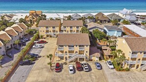 A coastal residential area with multiple two-story buildings, a parking lot, and a view of the ocean.