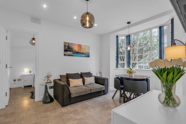 A modern living room with a sofa, a dining table, and a vase of flowers.