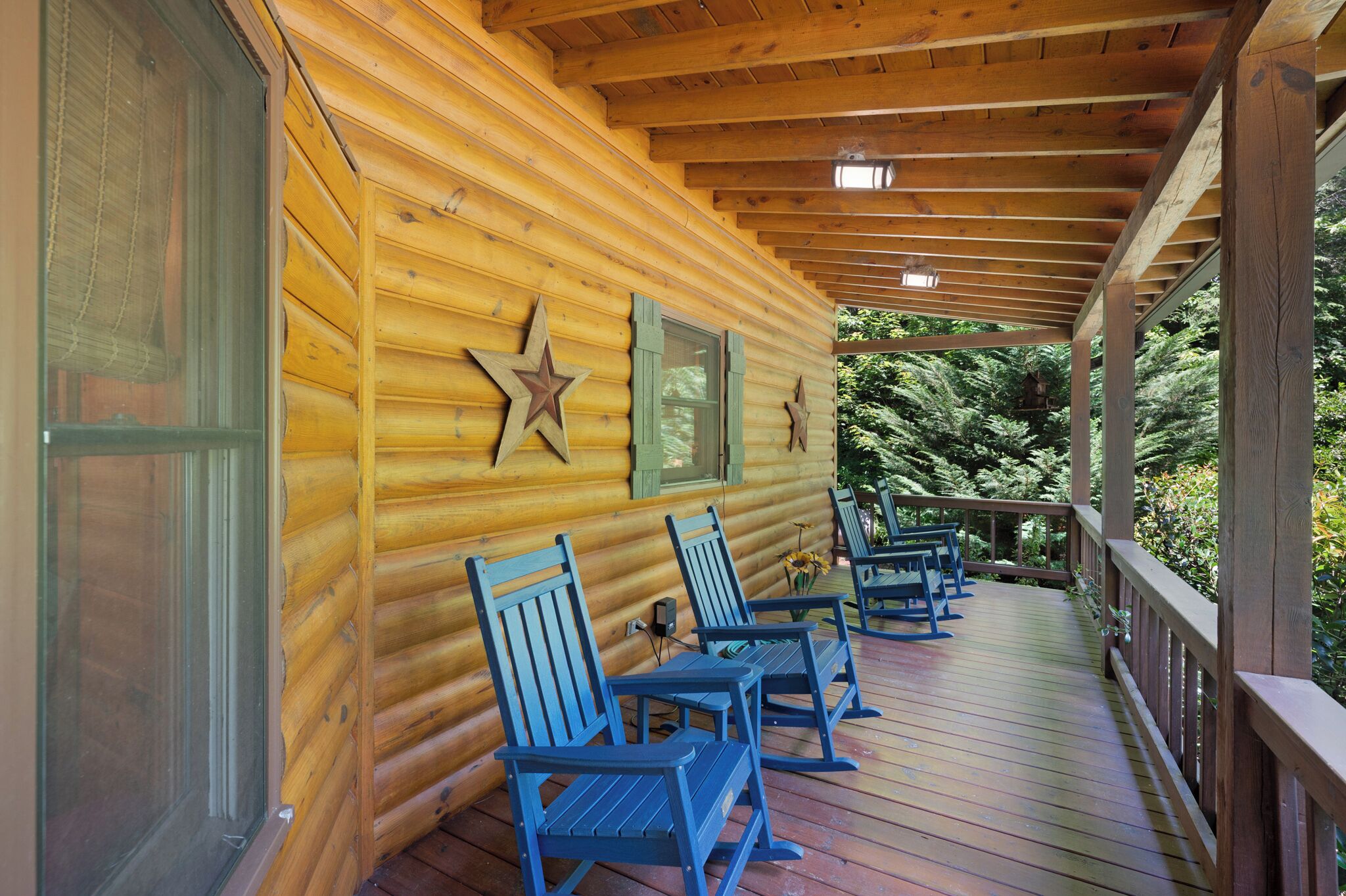 A wooden cabin with a porch, rocking chairs, and a star decoration on the wall.