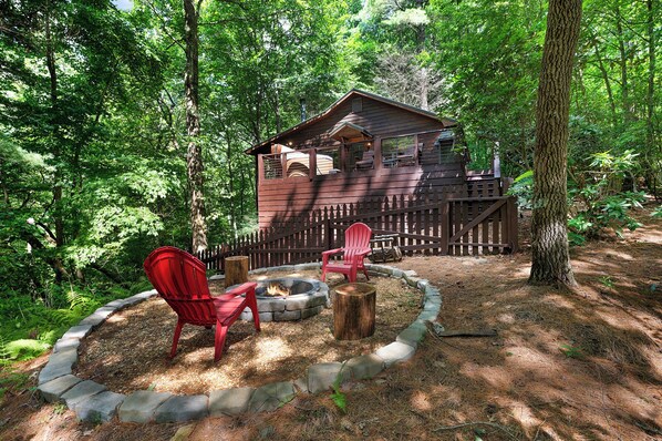 Une cabane avec un foyer, des chaises rouges et une bordure en pierre.