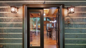 Interior de uma cabana de tronco com porta de madeira, área de bar e espaço para refeições.