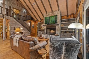 A spacious living room with a fireplace, a staircase, and a cozy seating area. - Mountaintown Creek Lodge – Creekside Cabin with Hot Tub, Game Room & Fishing (Ellijay)