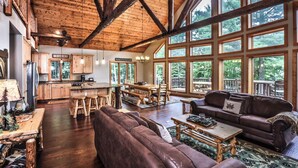 A spacious living area with a wooden ceiling, large windows, and a cozy fireplace. - NEW! Gorgeous Northwoods Home on the Eagle River Chain of Lakes (Eagle River)