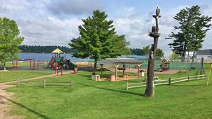 A park with playground equipment, picnic areas, and a view of a lake.