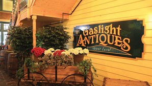 A sign for 'Gaslight Antiques' on a yellow wall, wooden barrels, and potted plants.