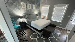 A bedroom with a bed, bedside tables, a chair, and a patterned rug. - Practically Perfect Place in Every Way (Pensacola)