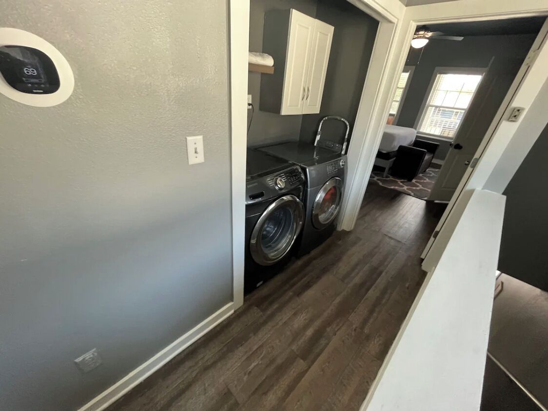 A laundry room with a washing machine and dryer, a small sink, and a cabinet.