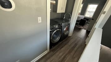 A laundry room with a washing machine and dryer, a small sink, and a cabinet.
