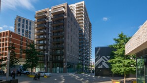 A multi-story building with balconies, a clear sky, and a few pedestrians. - 2 Bedroom Service Apt in Artillery Lane (London)