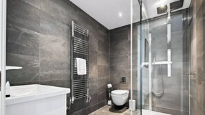 A modern bathroom with a glass-enclosed shower, a white bathtub, and a toilet. - 2 Bedroom Service Apt in Artillery Lane (London)