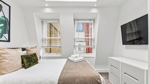 A bedroom with a bed, a desk, and two windows with blinds. - 2 Bedroom Service Apt in Artillery Lane (London)