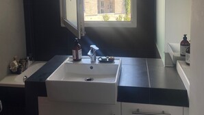 Une salle de bain moderne avec une grande fenêtre, un lavabo et un miroir.