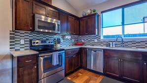 A modern kitchen with dark wood cabinets, stainless steel appliances, a checkered backsplash, and a large window. - Hull Street Loft 2 Bedroom Townhouse by RedAwning (Hood River)