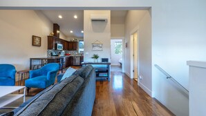 A modern living room with a sofa, a dining table, and a kitchen area with wooden cabinets and a microwave. - Hull Street Loft 2 Bedroom Townhouse by RedAwning (Hood River)