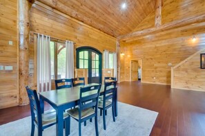 A wooden cabin interior with a dining table and chairs, large windows, and a staircase. - Sensational Views 4 Bedroom Cabin by Heavenly Views Resort (Gatlinburg)