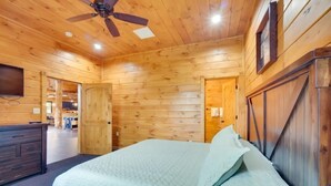 A wooden cabin bedroom with a bed, a ceiling fan, and a wooden door. - Sensational Views 4 Bedroom Cabin by Heavenly Views Resort (Gatlinburg)