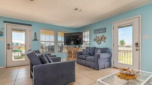 A living room with two grey sofas, a TV, and a glass coffee table.