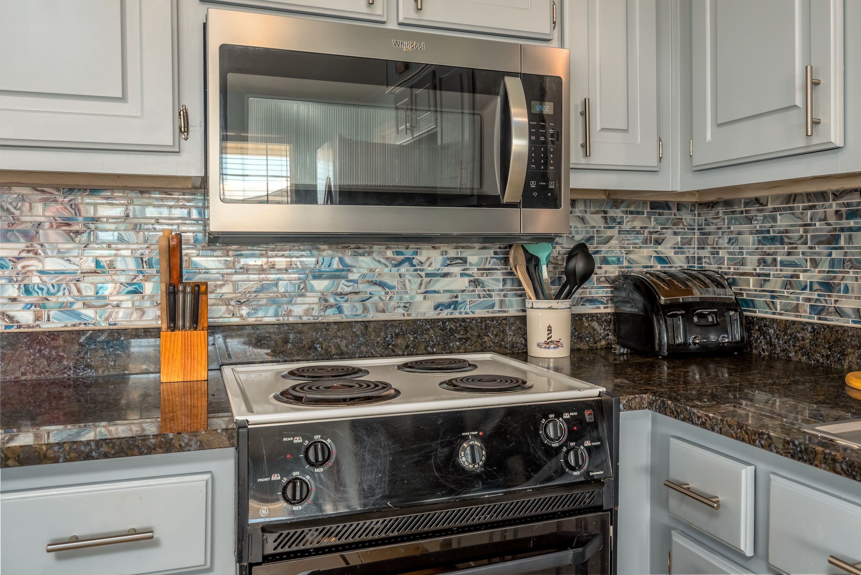 A kitchen with a stainless steel microwave, a gas stove, and a toaster.