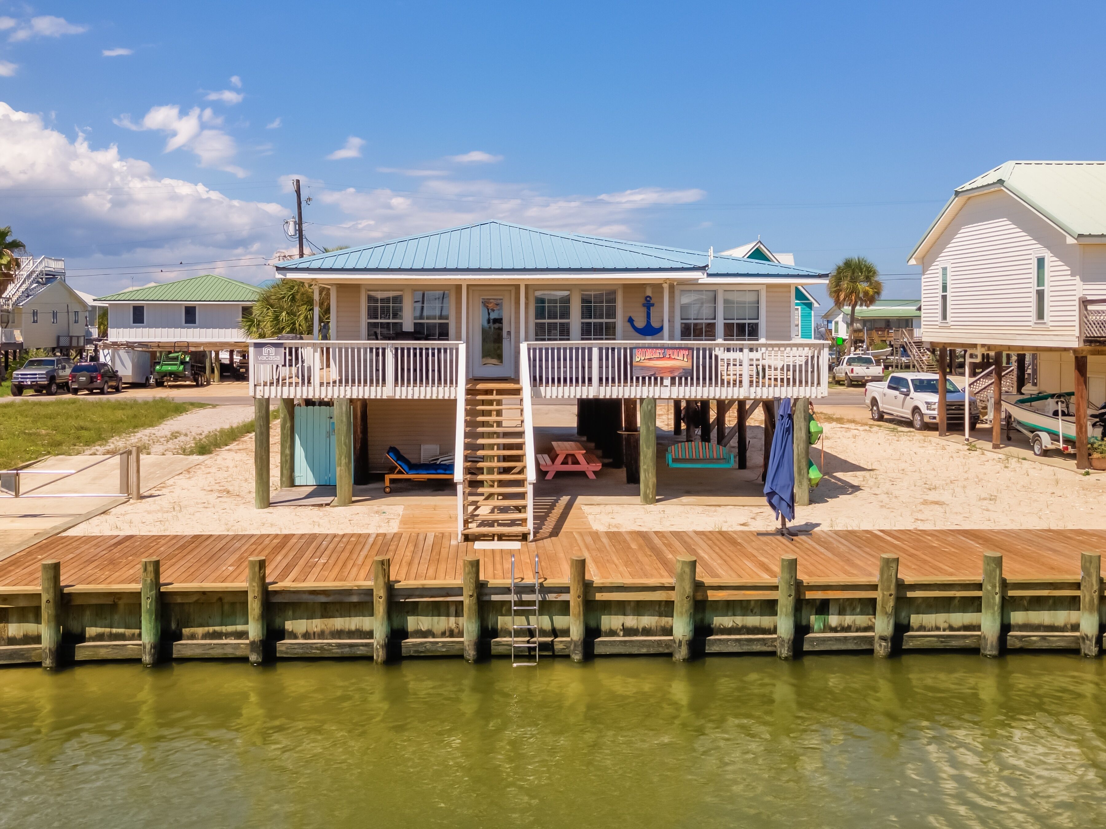 A beachfront house with a balcony, a deck, and a sign reading "Boney Bay".