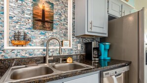 A kitchen with a double sink, a dishwasher, and a refrigerator.