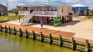 A beach house with a wooden deck, a blue roof, and a sign reading "Boys & Girls Camp".