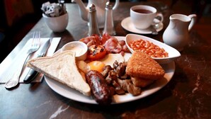 En frukosttallrik med rostat bröd, ägg, korv, bönor och bacon.