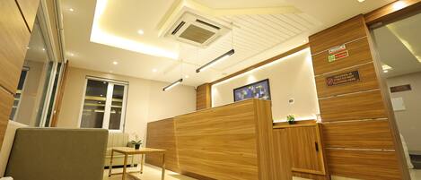 A modern reception area with a wooden reception desk, a seating area, and a large window.