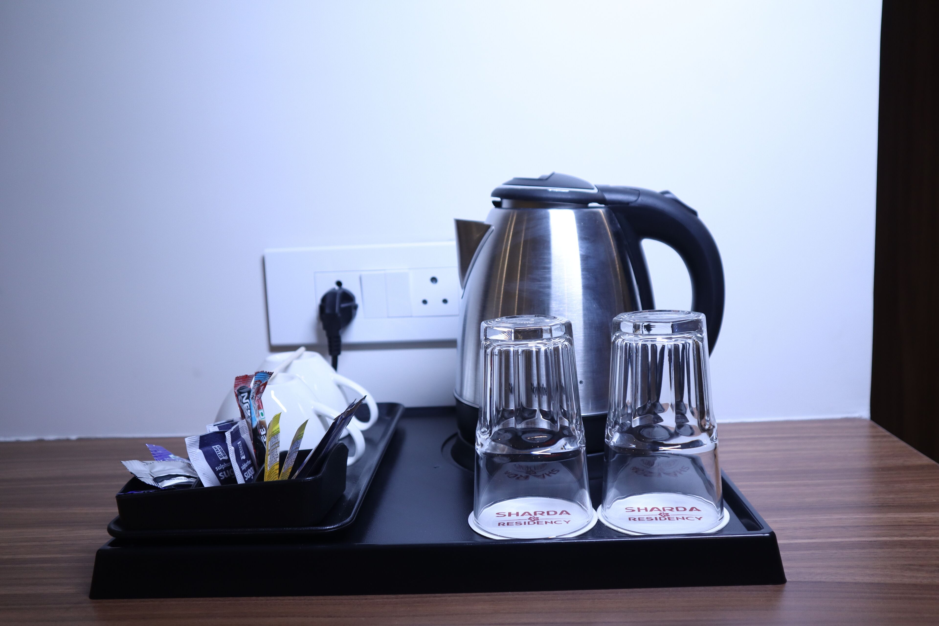 A kitchen setup with a kettle, two glass shakers, and a tray with packets.
