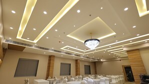 A conference room with round tables, white chairs, and a chandelier. - Hotel Sharda Residency (Patna)