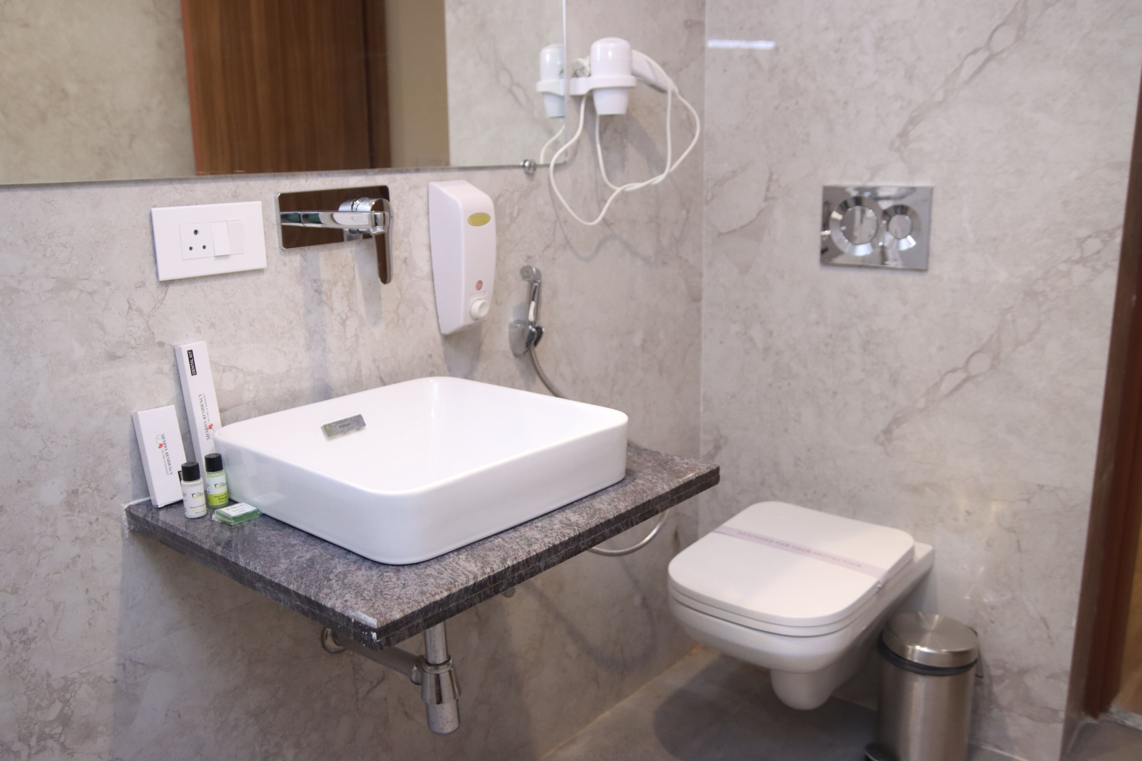 A bathroom with a white sink, a toilet, and a trash can.