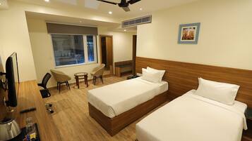 Una habitación de hotel con dos camas, televisión, escritorio y ventana.
