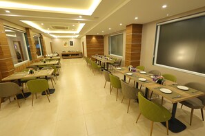 A conference room with multiple tables and chairs, equipped with nameplates, plates, and cutlery. - Hotel Sharda Residency (Patna)