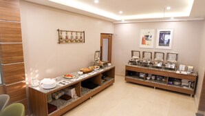 A modern hotel room with a wooden reception desk, a buffet counter with various food items, and a mirror on the wall. - Hotel Sharda Residency (Patna)