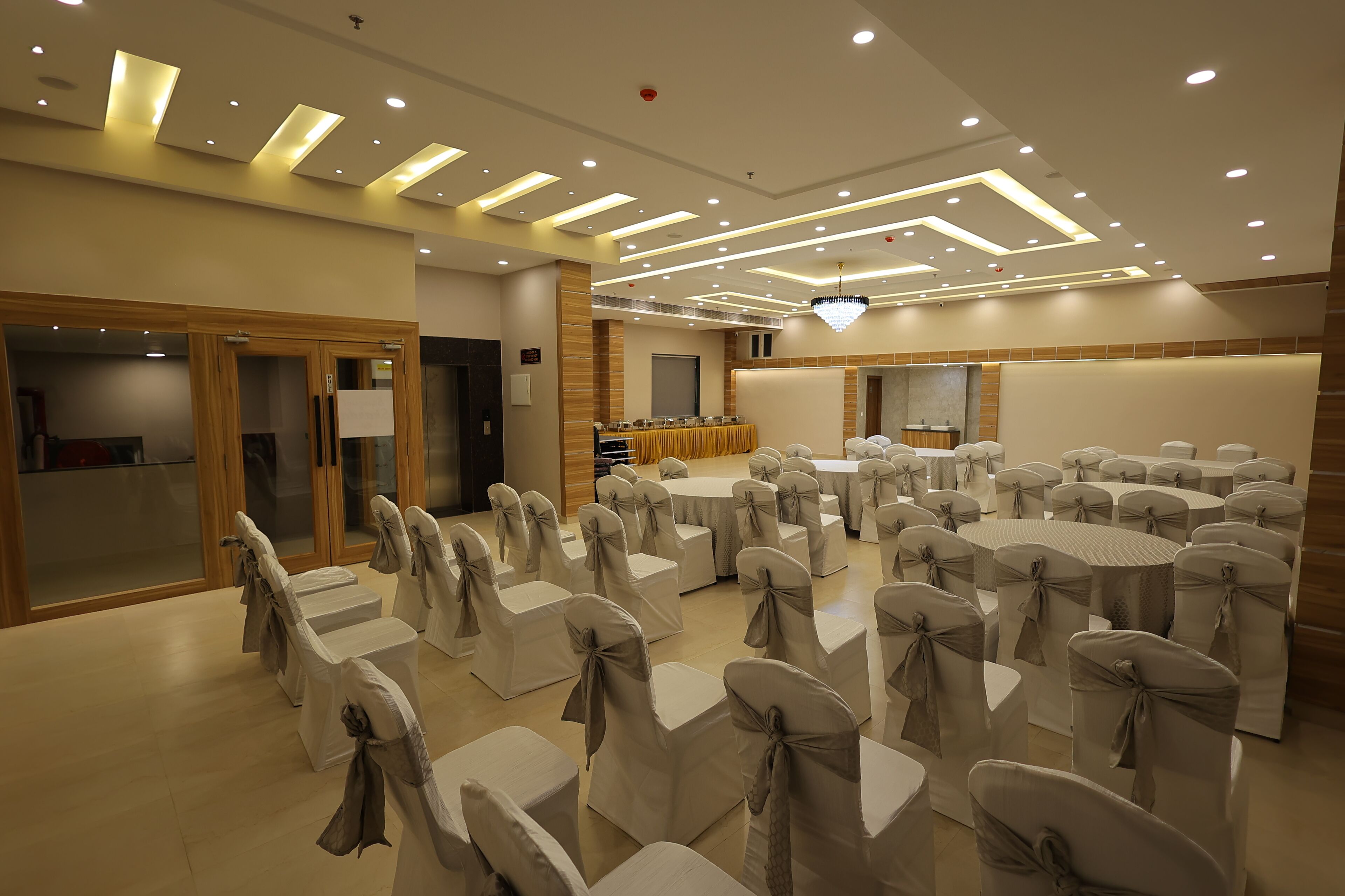 Un salón de conferencias con filas de sillas, un escenario y una zona de buffet.