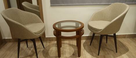 A room with two beige armchairs and a small wooden side table.