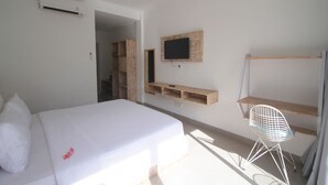 Un dormitorio con una cama, un televisor en la pared, un estante de madera y una silla.