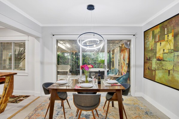A dining area with a wooden table, chairs, and a modern pendant light. - Midtown Mid-Century Modern, FREE golfcart. Close to downtown, 4BRs, 2baths. (Fairhope)