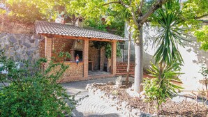 A stone building with a tiled roof, a brick patio, and a small outdoor seating area. - Villa Fuji Sierra de la Pandera (AN)