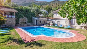 A pool area with a stone wall, a small building, and a view of hills in the background. - Villa Fuji Sierra de la Pandera (AN)